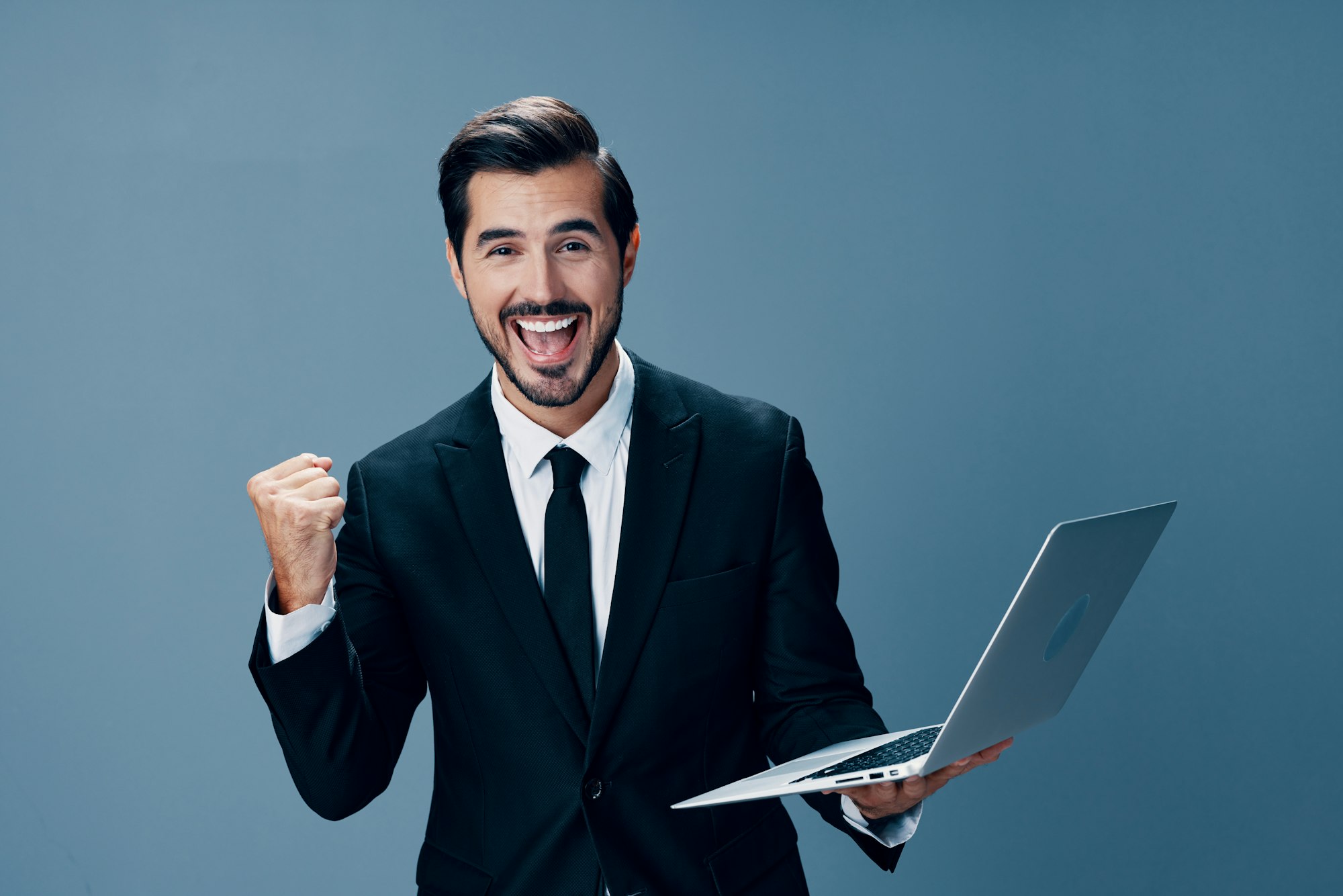 Man business looks into laptop and works online smiling fist up online in business suit video call